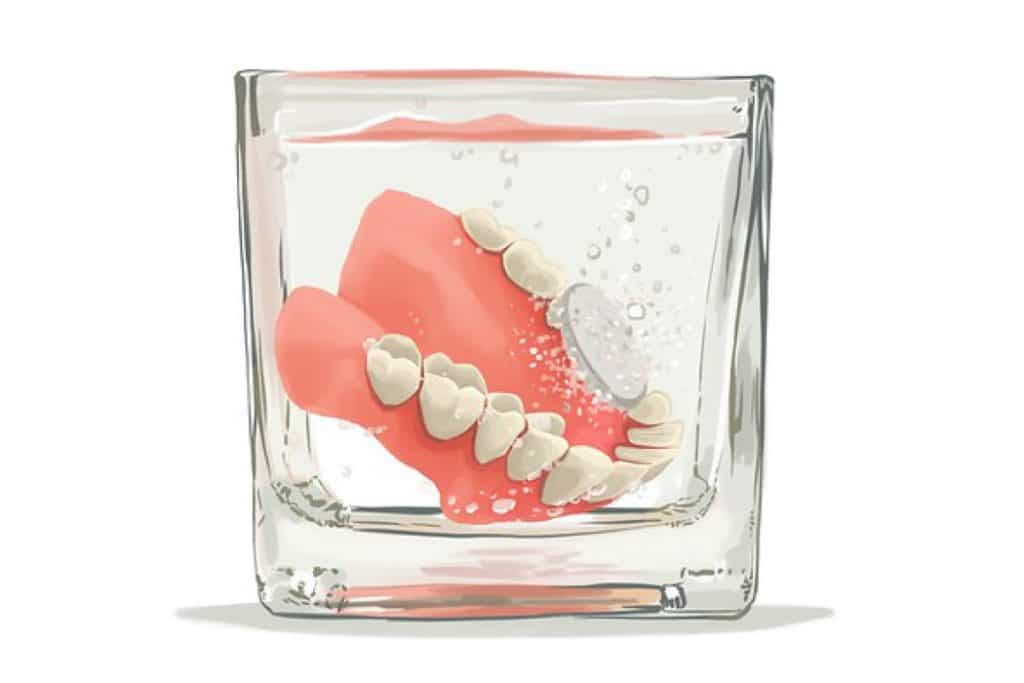 Dentures soaking in a jar with a cleaning tablet.