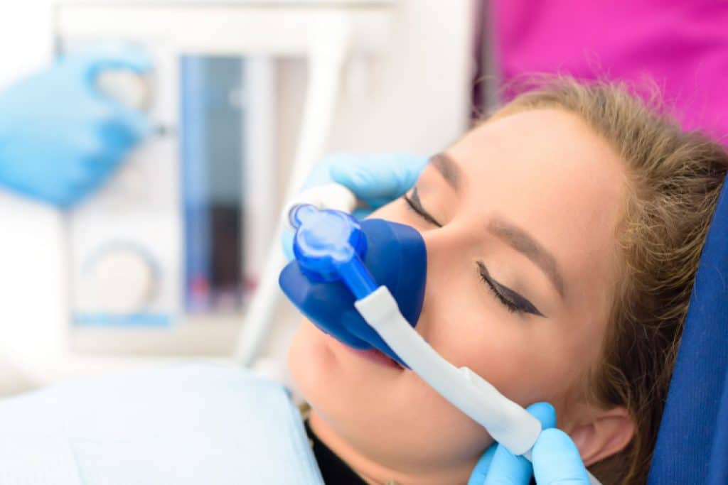 Woman getting dental sedation through a mask administering nitrous oxide.