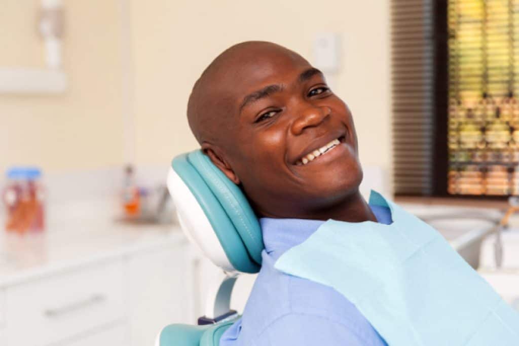 Smiling black man in the dental chair for an oral cancer screening.