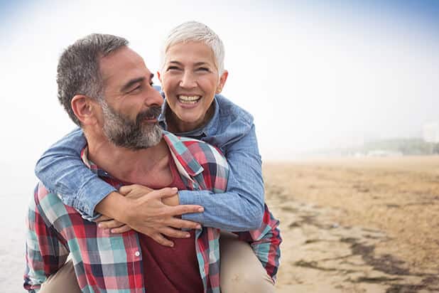 happy senior couple walking on the beach